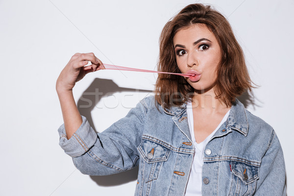 Young attractive lady stretching bubble gum. Stock photo © deandrobot