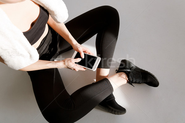 Imagen deportivo mujer sesión las piernas cruzadas escribiendo Foto stock © deandrobot