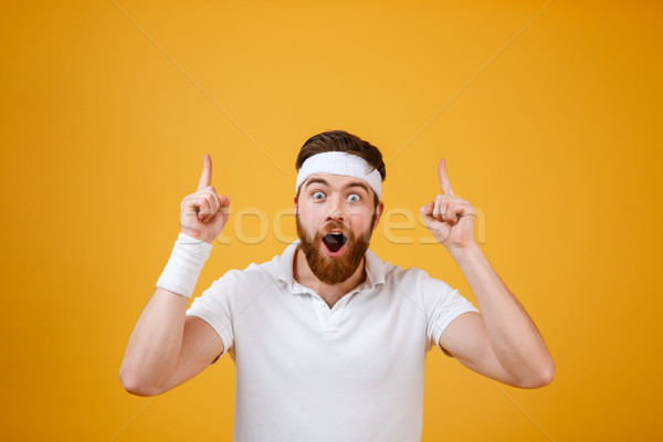 Suprised sportsman pointing up Stock photo © deandrobot