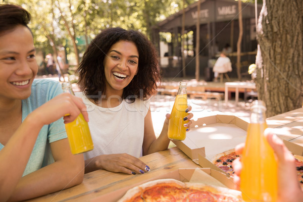 Happy young multiethnic friends students outdoors drinking juice eating pizza Stock photo © deandrobot