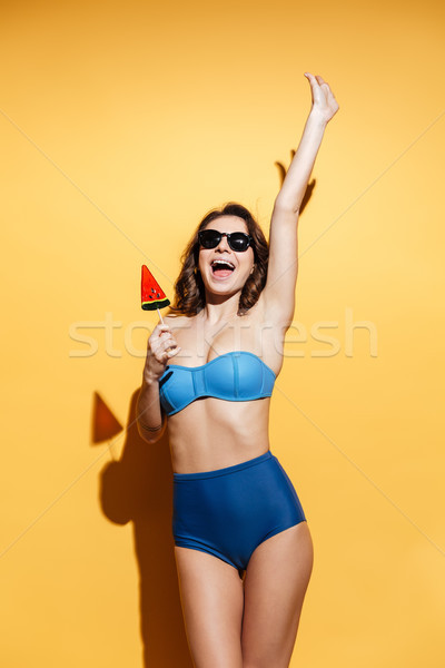 Cheerful young lady in swimwear eating candy. Stock photo © deandrobot