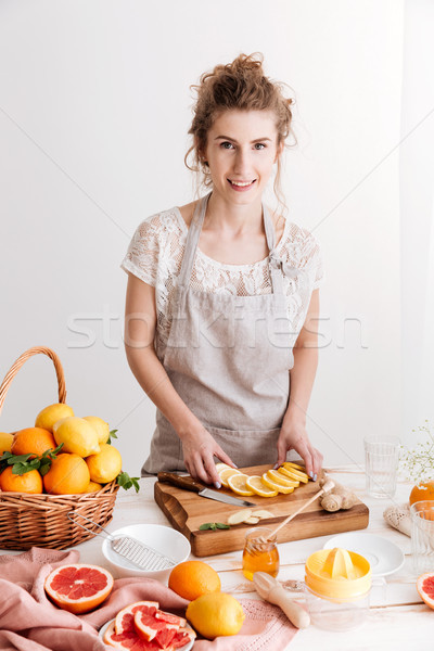 Happy woman cut the lemon. Looking at camera. Stock photo © deandrobot