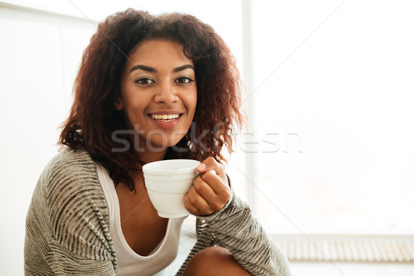 Cute woman with cup of tea sitting on floor Stock photo © deandrobot
