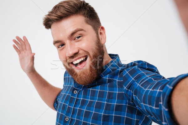 Happy bearded man in checkered shirt making selfie Stock photo © deandrobot