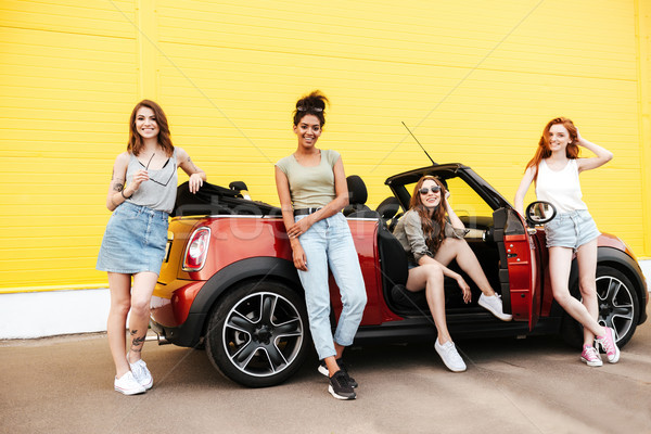 Happy emotional four young women friends standing near car Stock photo © deandrobot
