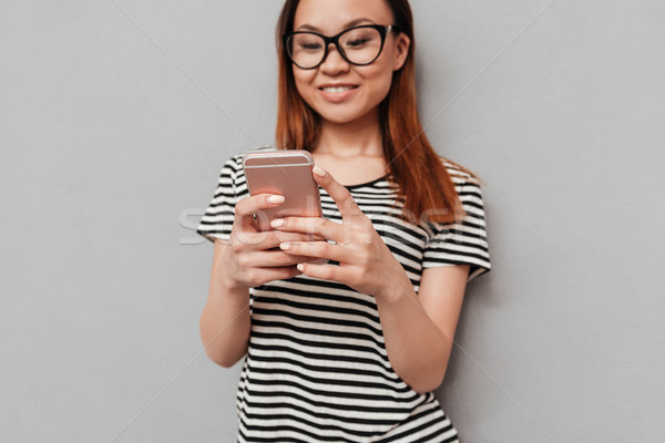 Happy young pretty woman chatting by phone. Focus on phone. Stock photo © deandrobot