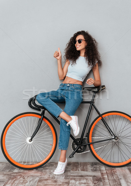 Full length image of pretty smiling curly woman in sunglasses Stock photo © deandrobot