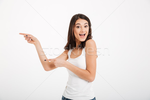 Portrait of a happy girl dressed in tank-top pointing fingers Stock photo © deandrobot