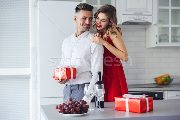Young lady hug and looking at her man who holding present at home Stock photo © deandrobot
