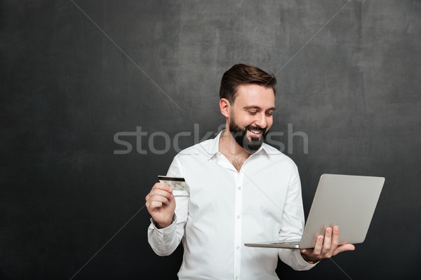 Portrait of cheerful man doing online payment in internet using  Stock photo © deandrobot