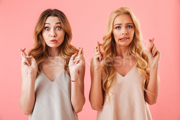 Two worried pretty women in pajamas praying with crossed fingers Stock photo © deandrobot