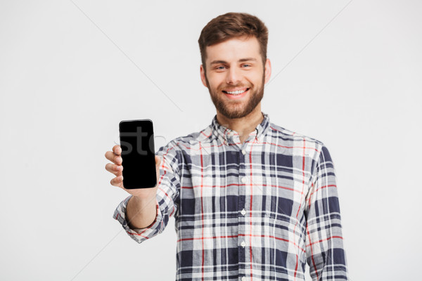 Portret jonge man tonen scherm mobiele telefoon geïsoleerd Stockfoto © deandrobot
