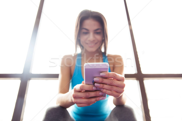 Happy beautiful woman using smartphone at gym Stock photo © deandrobot