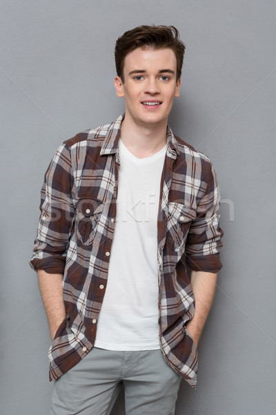 Handsome young man in checkered shirt posing and smiling  Stock photo © deandrobot