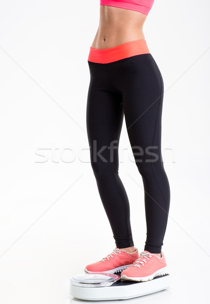 Closeup of fitness woman legs standing on weighing scale  Stock photo © deandrobot