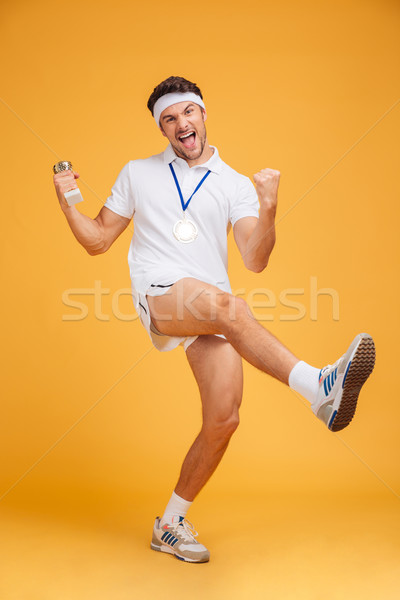 Joyful sportsman with golden medal and trophy cup celebrating victory Stock photo © deandrobot