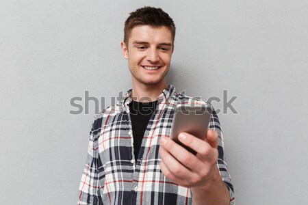Young handsome smiling man pointing finger at takeaway coffee cup Stock photo © deandrobot