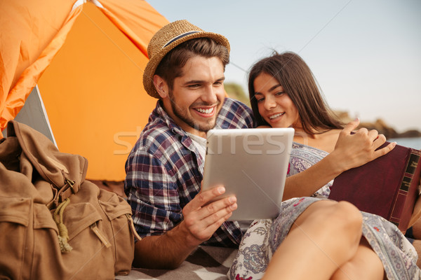 Couple sitting at tent using tablet computer and reading book Stock photo © deandrobot