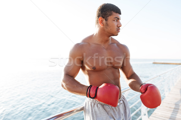 Afro american sportsman in red gloves doing exercises outdoors Stock photo © deandrobot