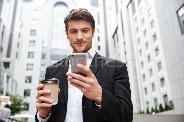 Businessman using cell phone and drinking coffee in the city Stock photo © deandrobot