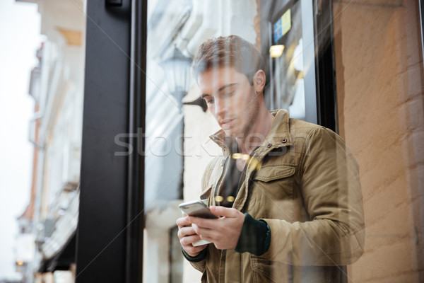 Young man walking and chatting by his phone Stock photo © deandrobot