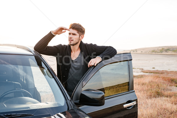 Young man standing at his car parked on the seaside Stock photo © deandrobot