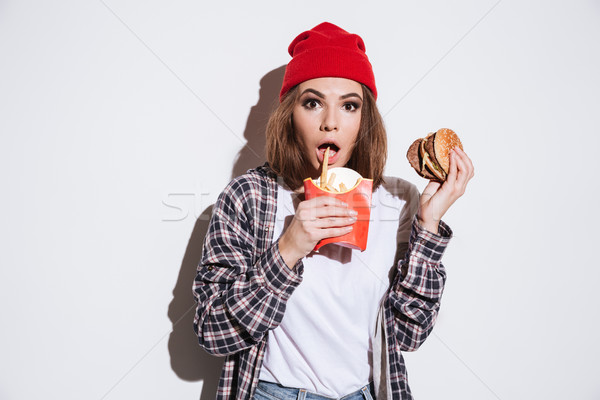 Stock photo: Hungry woman holding fries and burger