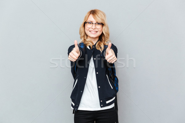 Stock photo: Cheerful young lady student showing thumbs up.