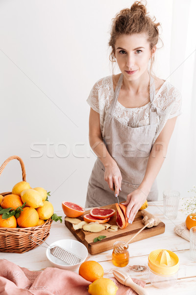 Cheerful lady standing near table with a lot of citruses Stock photo © deandrobot
