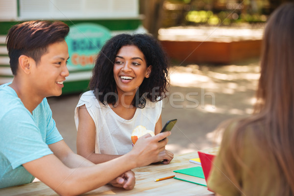 Stock photo: Side view of happy three friends sitting by the table
