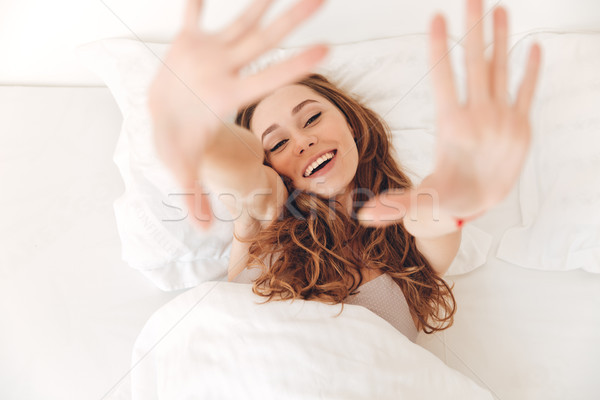 Happy pretty lady lies in bed indoors. Looking camera. Stock photo © deandrobot