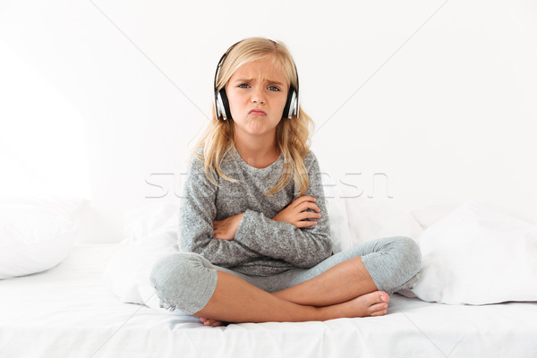 Upset female kid in headphones sitting with crossed arms and leg Stock photo © deandrobot