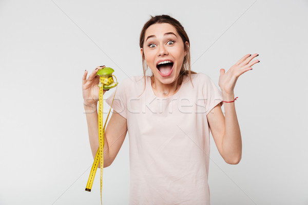 Portrait of an excited cheerful girl holding half eaten apple Stock photo © deandrobot