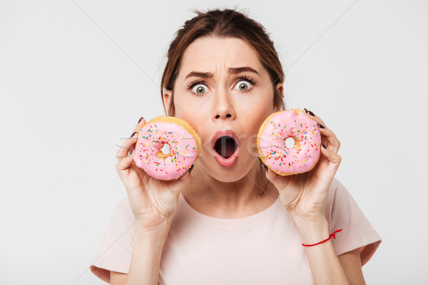 Close up portrait of a shocked pretty girl holding donuts Stock photo © deandrobot