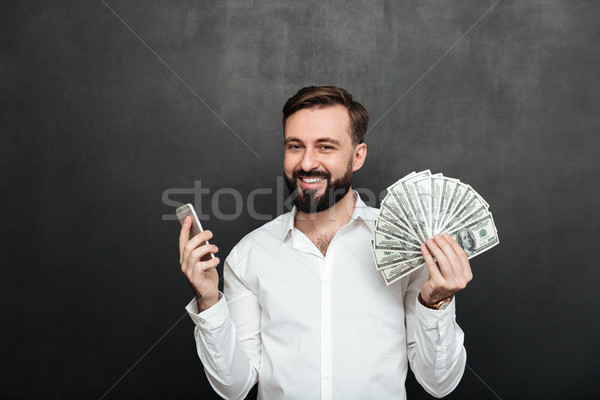 Portrait of cheerful man in white shirt winning lots of money do Stock photo © deandrobot