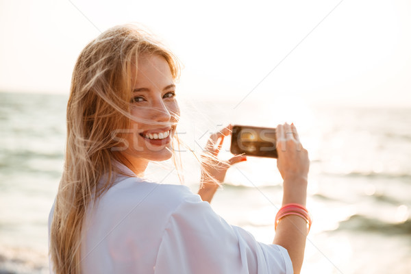 Photo of adorable blonde woman 20s smiling, and taking photo of  Stock photo © deandrobot