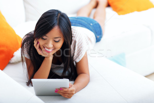 Happy young asian woman browsing internet with her tablet Stock photo © deandrobot