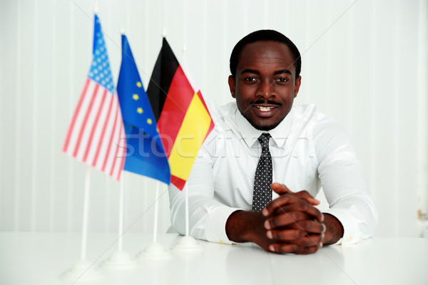 Cheerful businessman sitting at the table at his workplace Stock photo © deandrobot