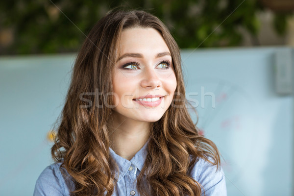 Pretty cheerful curly young woman in formalwear looking away Stock photo © deandrobot