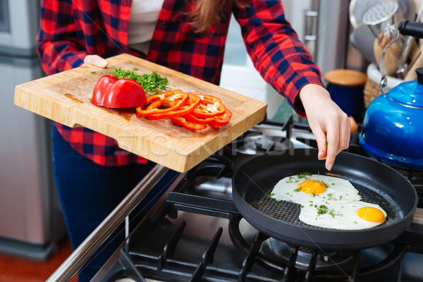 Stock photo: Woman put dill into scrambled eggs on frying pan