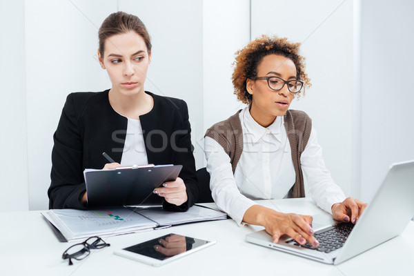 Two focused businesswomen working using clipboard and laptop Stock photo © deandrobot