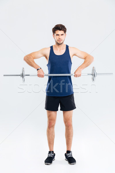 Full length of handsome young sportsman training and lifting barbell Stock photo © deandrobot