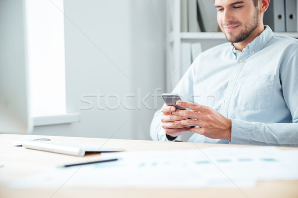 Cropped image of a businessman sitting and using smartphone Stock photo © deandrobot