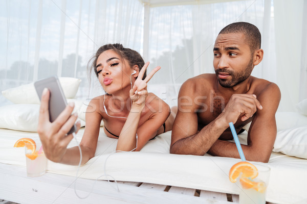 Girl making selfie with displeased boyfriend Stock photo © deandrobot