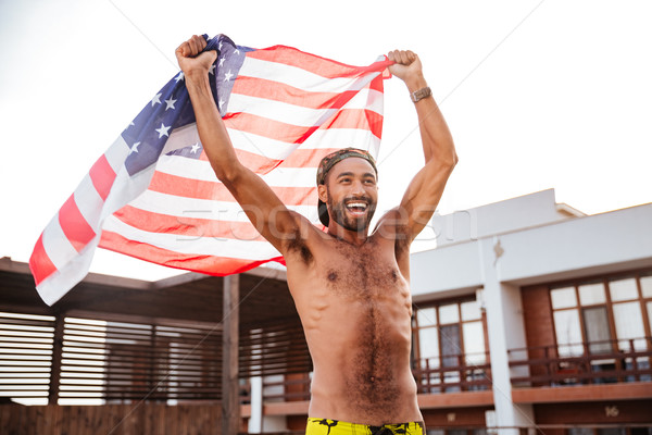 Cheerful african american man holding flag of United States Stock photo © deandrobot