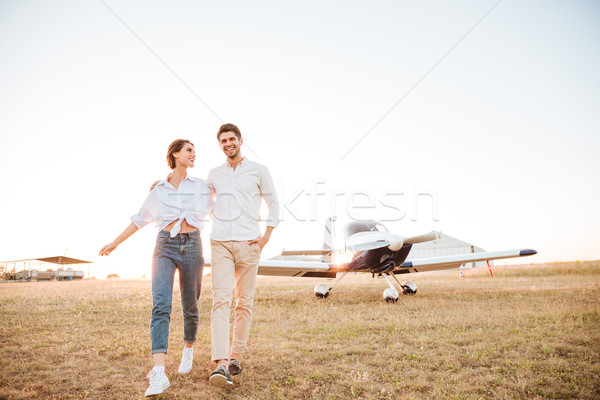 Couple walking together across the field with airplane on background Stock photo © deandrobot