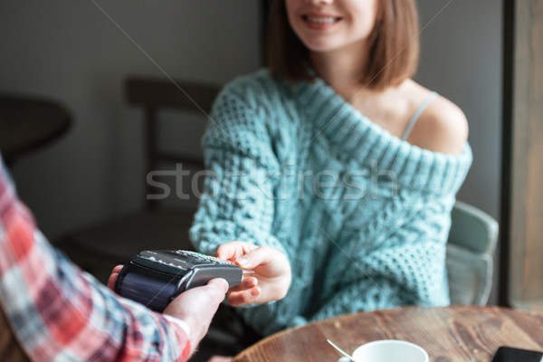 Woman sitting near window and pays purchases with card. Stock photo © deandrobot