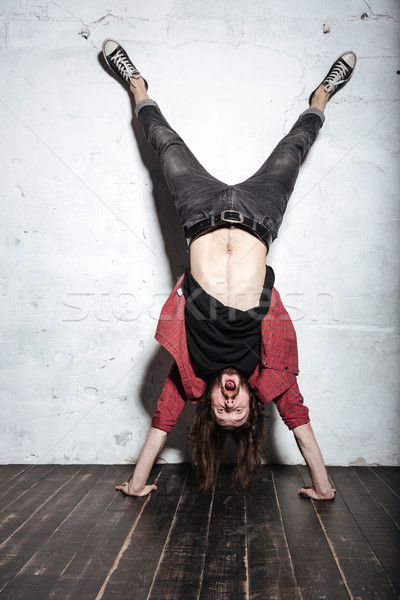 Emotional bearded hipster man standing on hands Stock photo © deandrobot