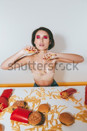 Tempting woman in bra throwing french fries on her body Stock photo © deandrobot