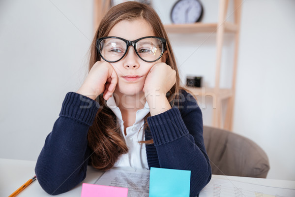 Sad bored little girl in glasses sitting at the table Stock photo © deandrobot